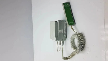 Green and gray medical call button with coiled cord attached to wall-mounted control box cbj linak cbj2005hd112xx4