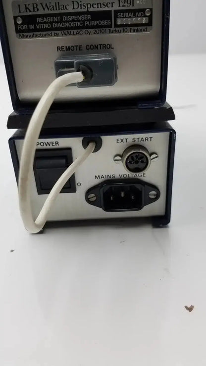 Black and silver lkb wallac 1291 reagent dispenser with white power cord connected to rear panel for in vitro diagnostic purposes