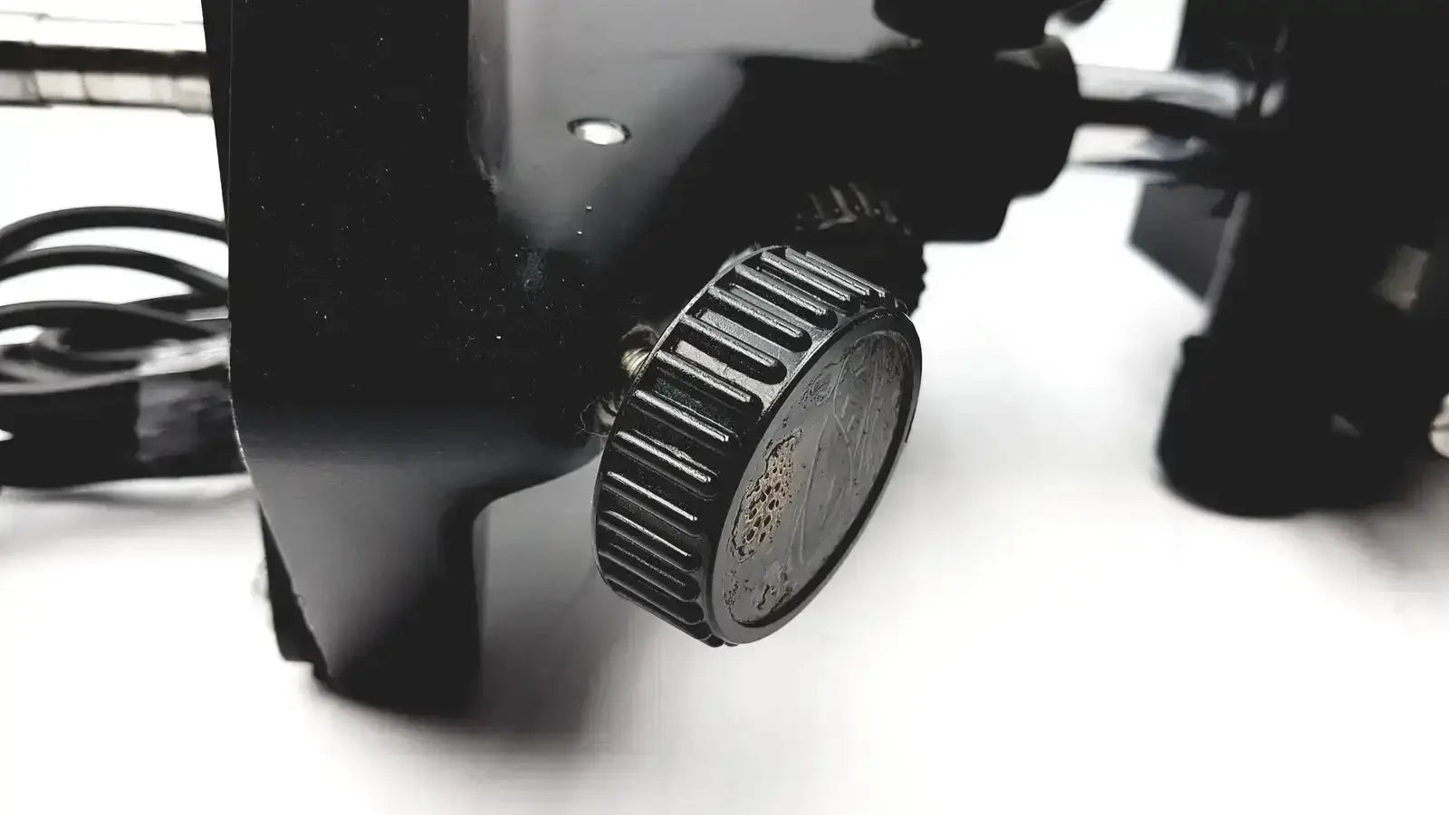 Black textured knob with ridged edges and embossed design on lombart instrument keratometer model 12515 face