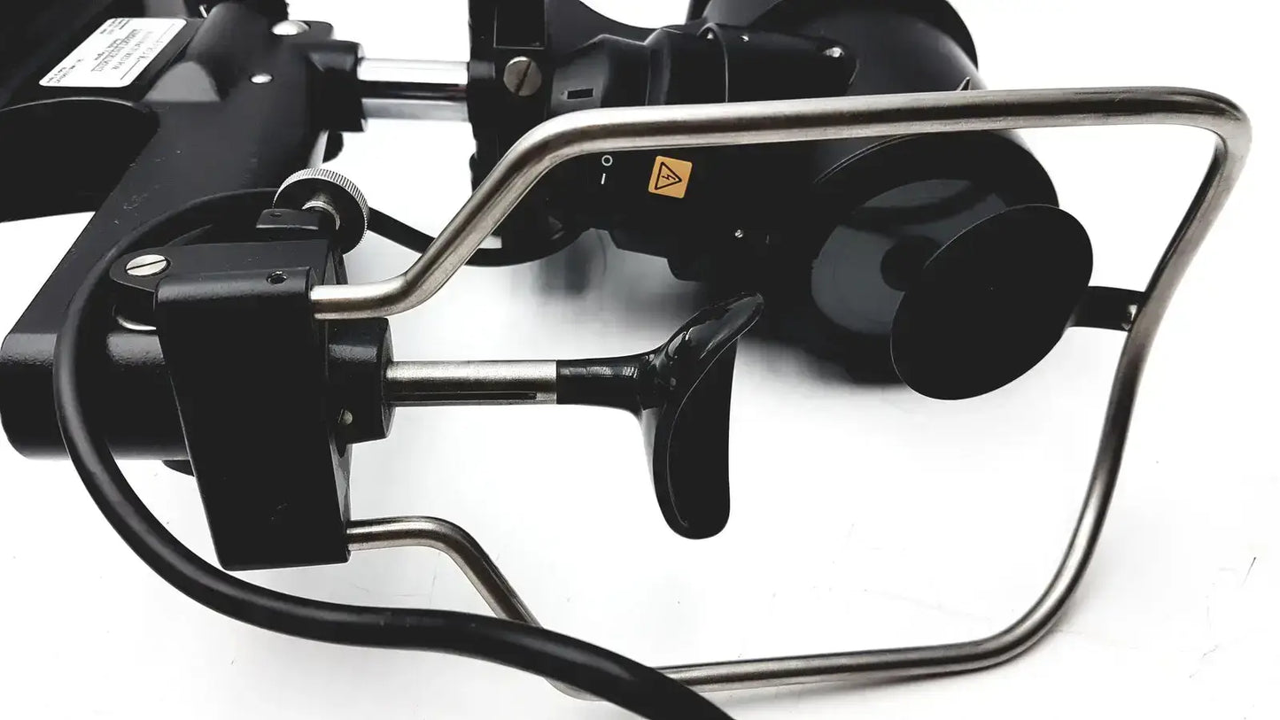 Black and silver industrial robotic arm with metallic joints and warning label on lombart instrument keratometer model 12515