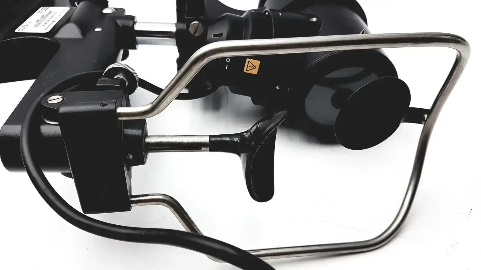 Black and silver industrial robotic arm with metallic joints and warning label on lombart instrument keratometer model 12515
