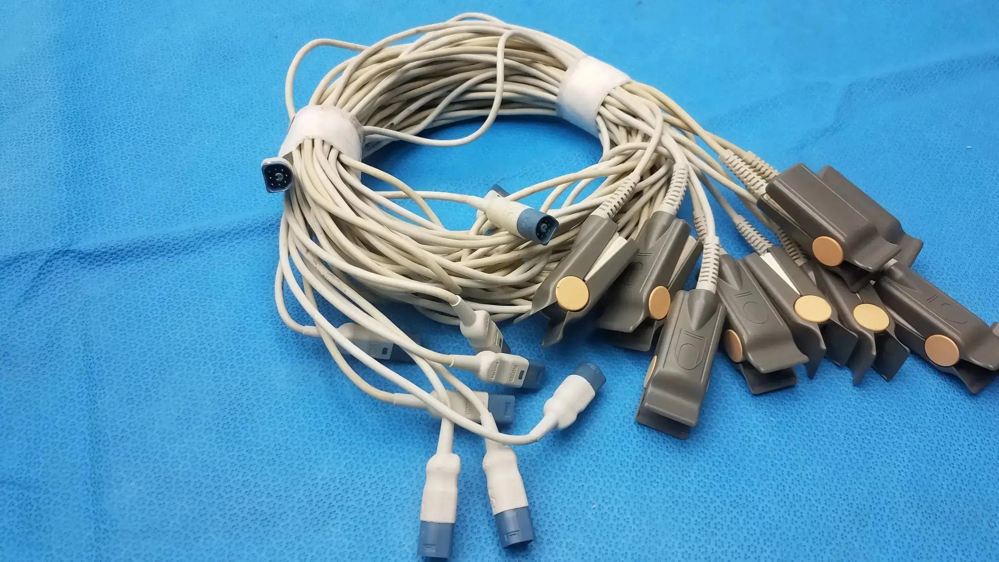 A bundle of beige medical ecg lead wires with gray clamps and blue connectors for adult finger clip sensor use