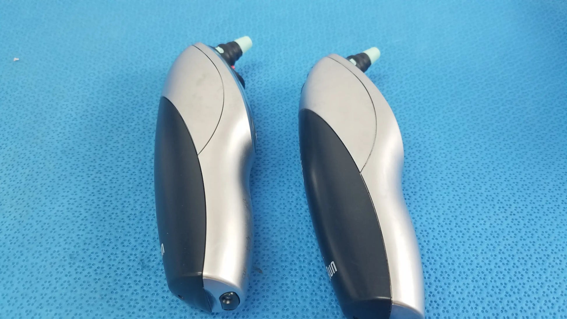 Silver and black ergonomically designed electronic earwax removal devices in a lot of 2 with welch allyn charging dock for reuse medical equipment