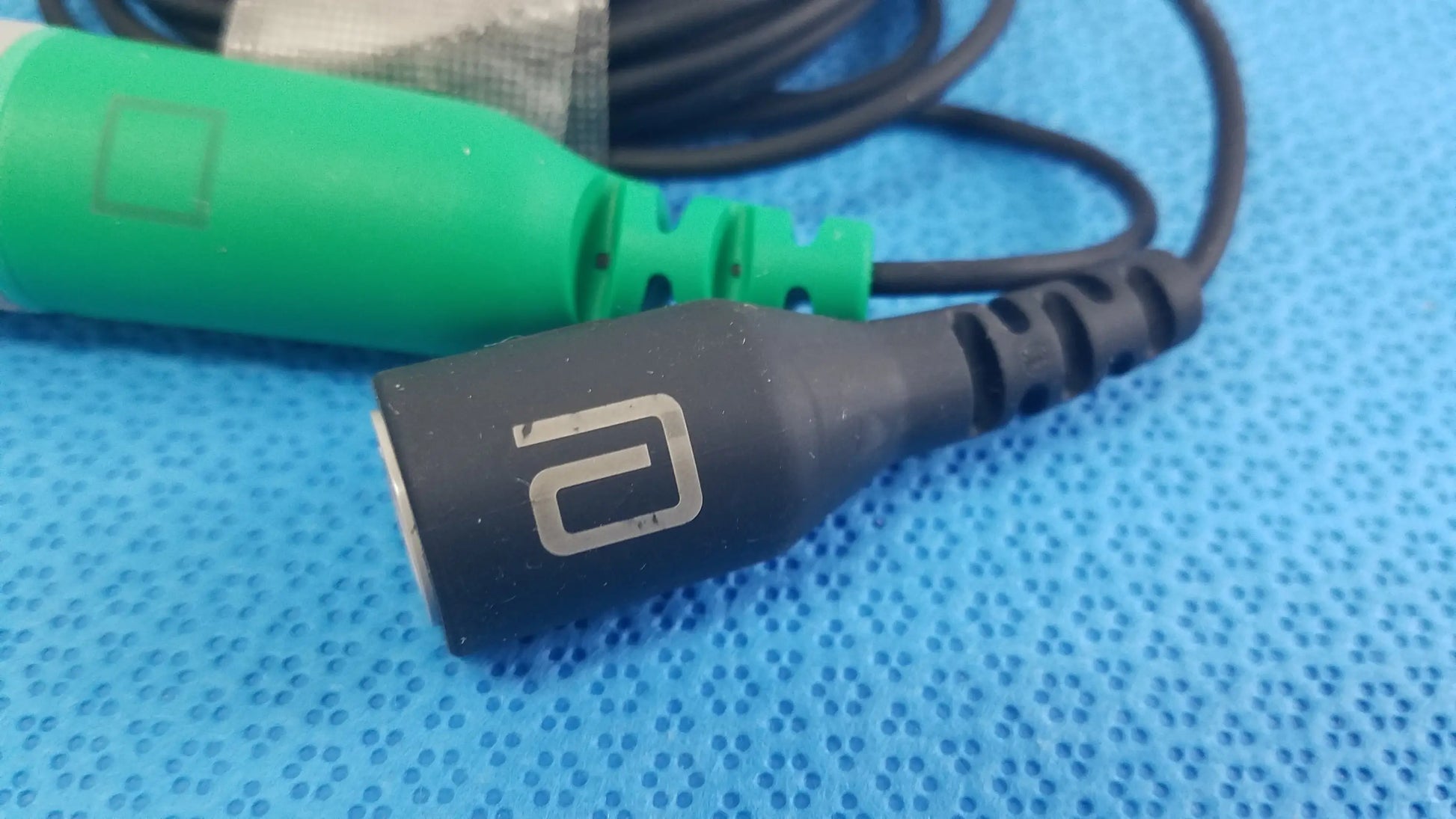 Black audio catheter connector cable with silver logo and textured grip for reuse medical equipment applications