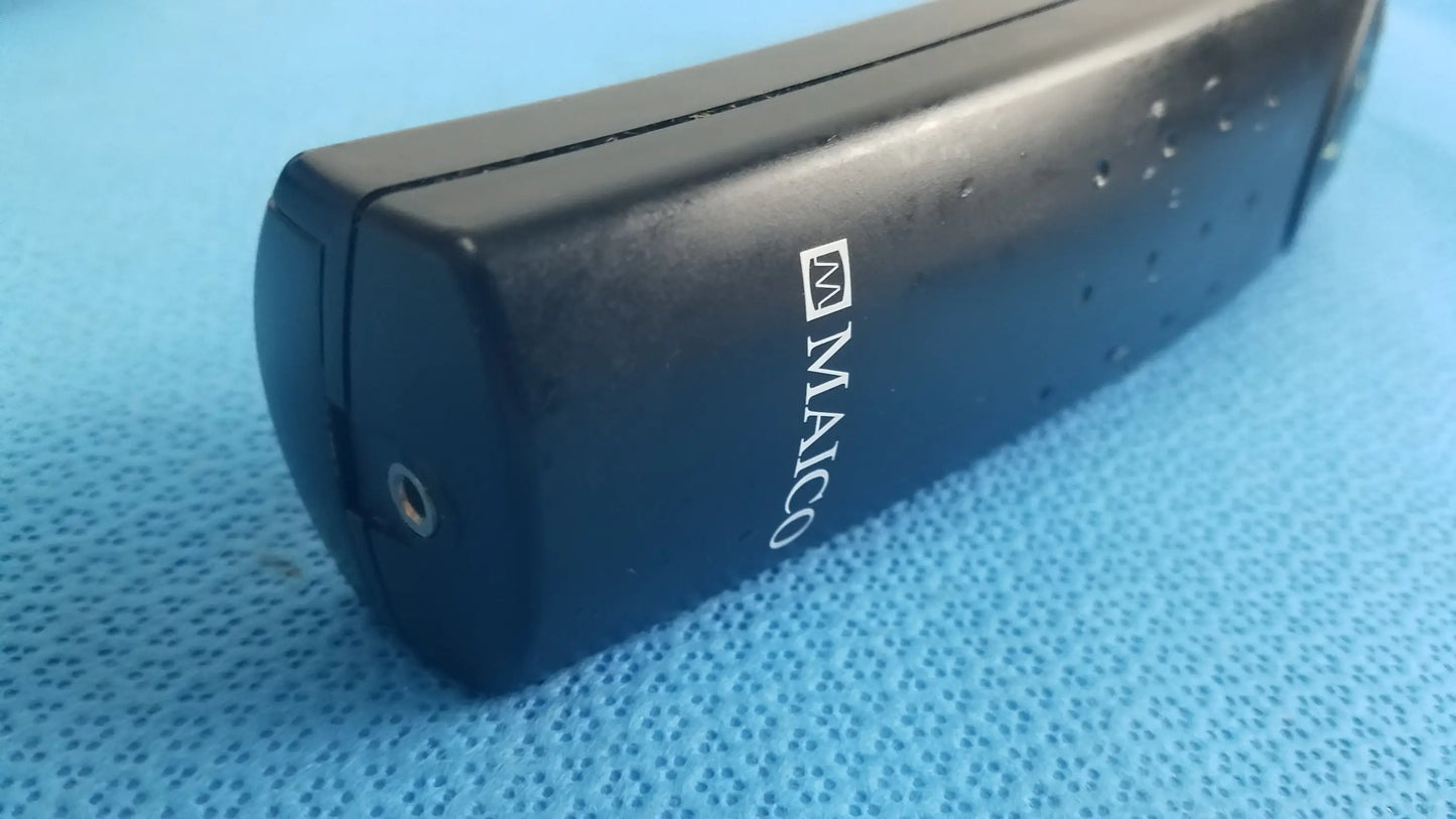 Black maico branded portable charger with matte finish and side perforations for handheld auditory medical equipment