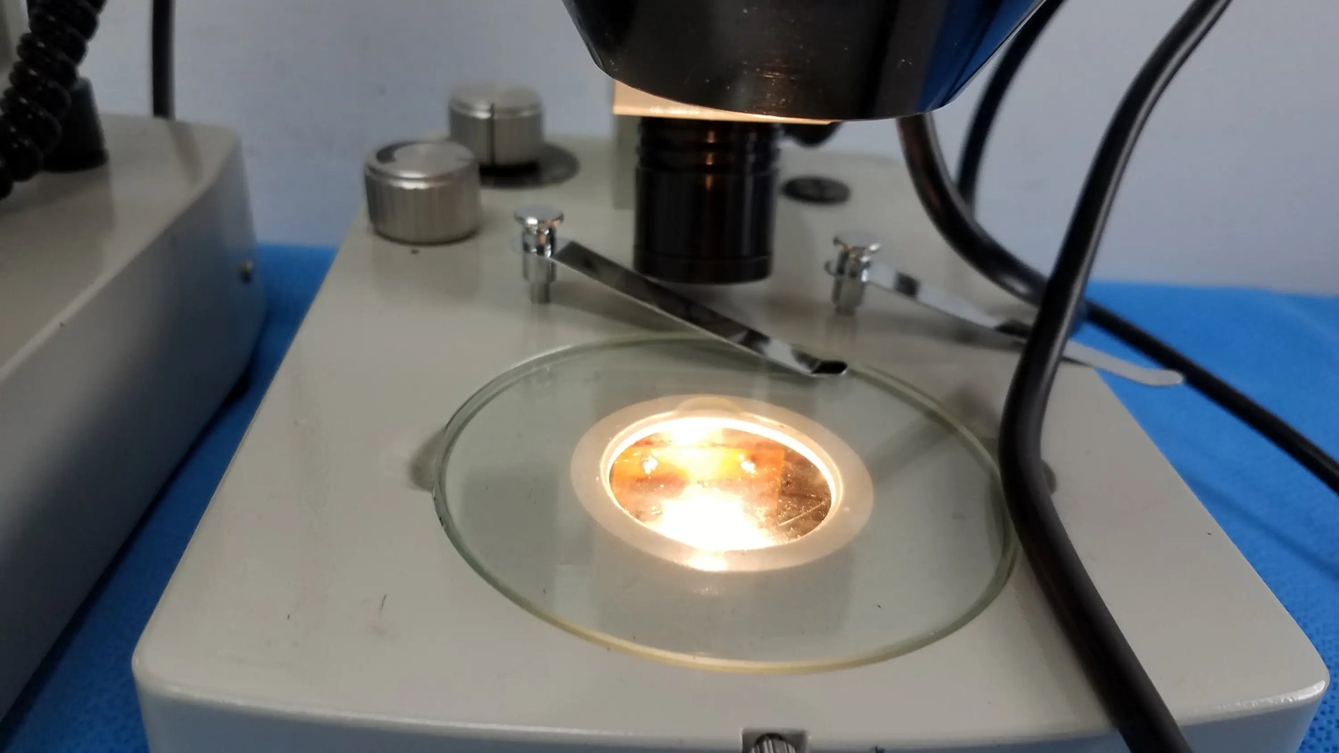 A circular glass stage with a bright warm light at center on lot of 2 Meiji Techno EMT-1 stereo microscope medical equipment
