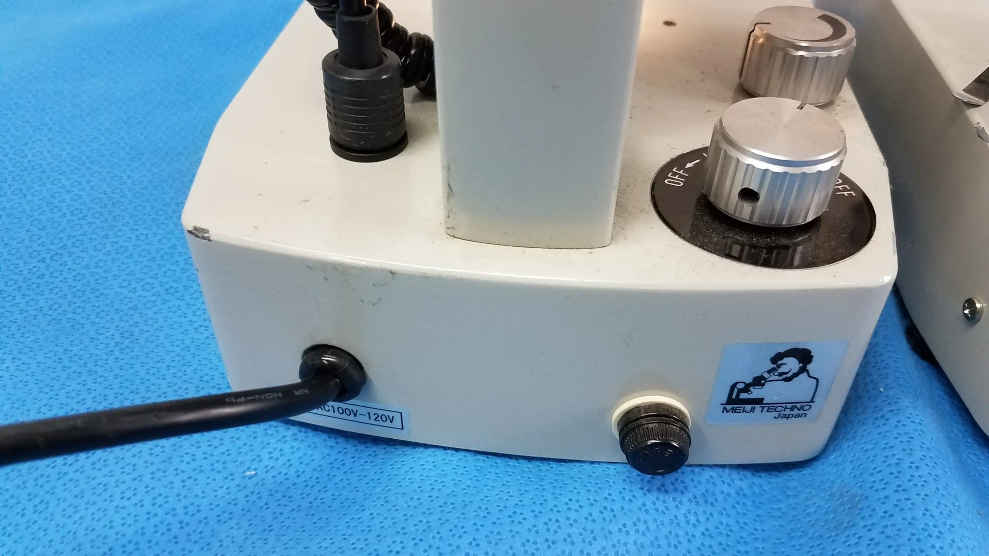 White rectangular base of meiji techno stereo microscope with silver knobs and black power cord for medical equipment use