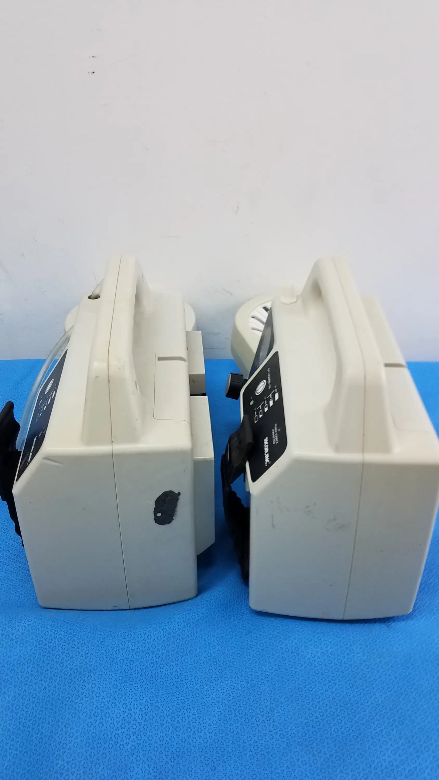 Two beige sscor 2314 duet portable aspirators with black control panels on blue surface medical equipment