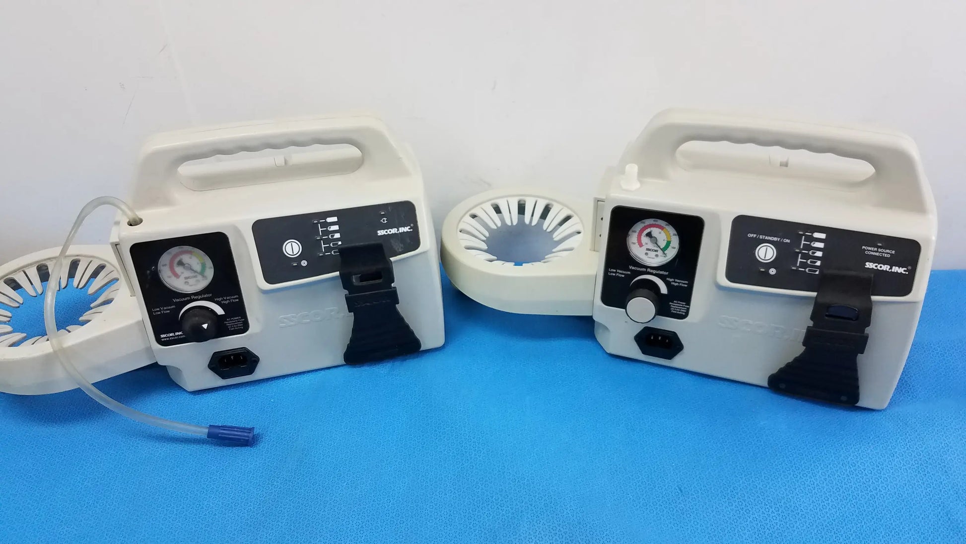 Two white portable aspirator units with black control panels and pressure gauges by Secor Inc duet portable aspirator medical equipment