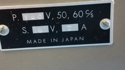 Back side of a black rectangular label with white text and silver screws on a lot of 2 stereo microscope with ck inverted binocular microscope showing electrical specifications and made in japan