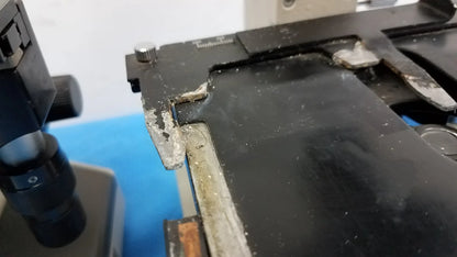 Black plastic microscope stage with worn edges and silver screw cap on Wesco and Olympus CH-2 laboratory medical equipment for reuse medical equipment