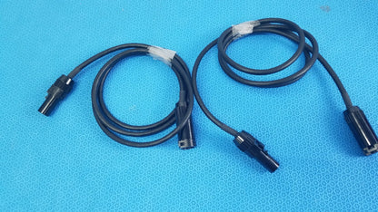 Lot of 3 black coiled mc4 solar connector extension cables with plastic connectors and white tape wraps for pv systems