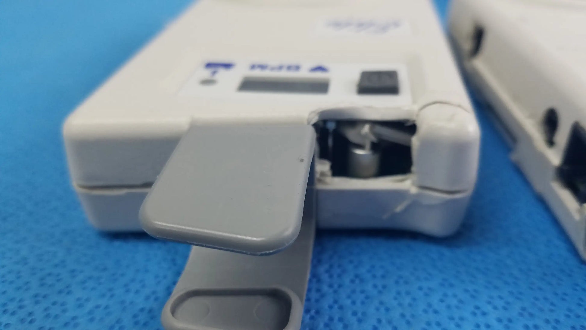 White plastic Natus Neurology Elite 200R handheld Doppler with gray hinged cover showing internal components medical equipment