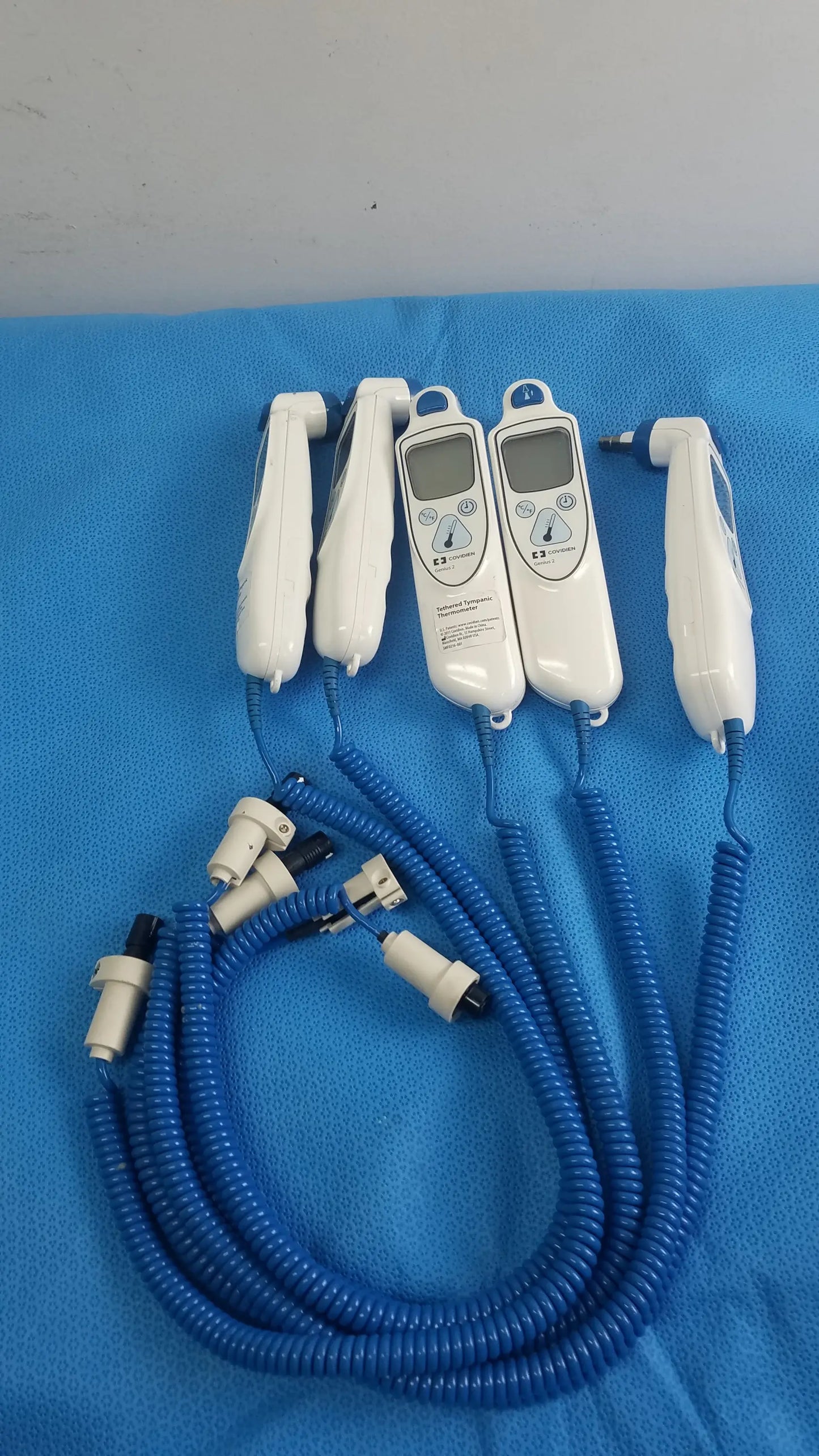 Lot of 4 coviden genius 2 tethered tympanic thermometers white handheld medical equipment with digital displays and blue cords for reuse medical equipment