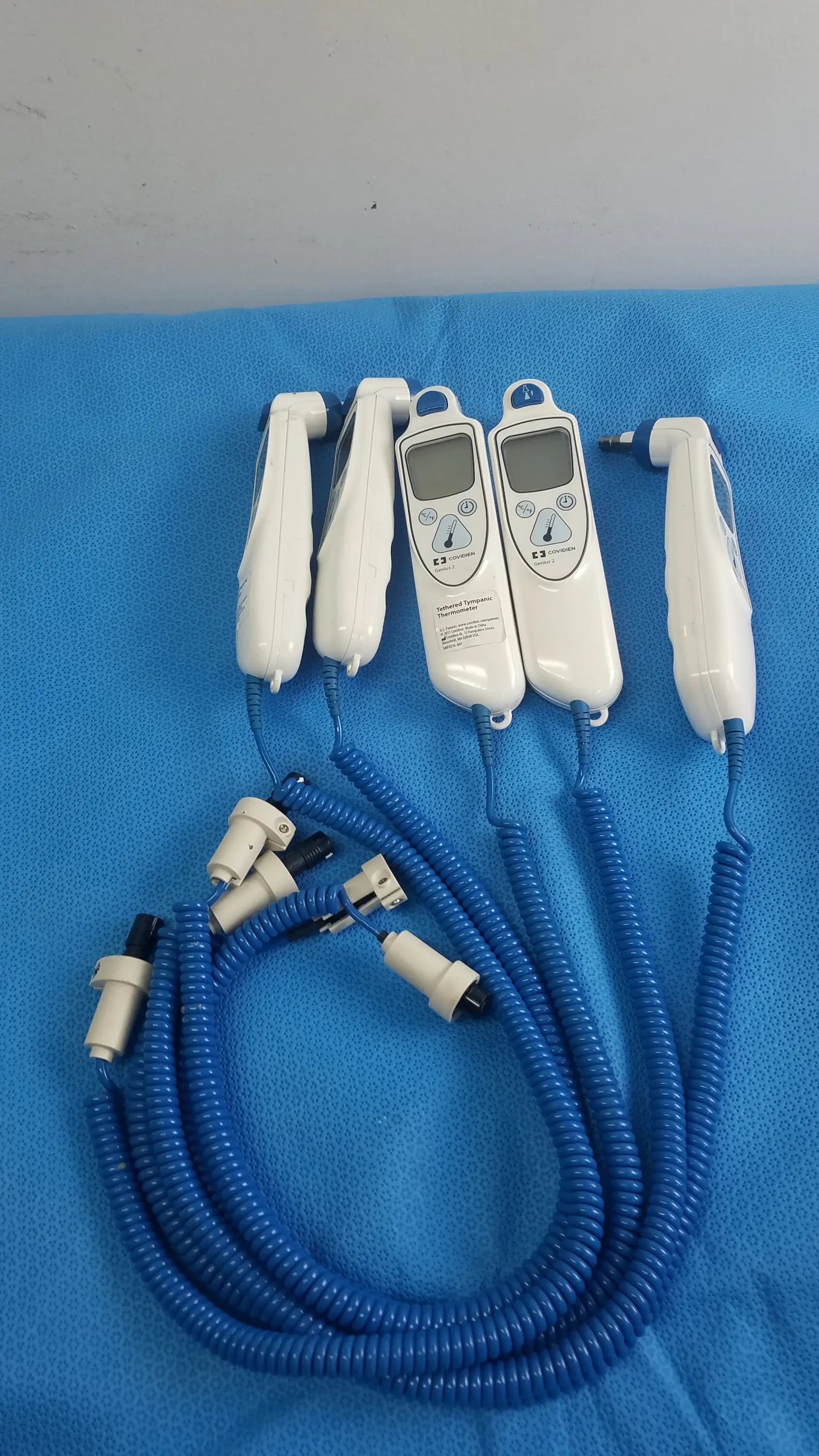 Lot of 4 coviden genius 2 tethered tympanic thermometers white handheld medical equipment with digital displays and blue cords for reuse medical equipment