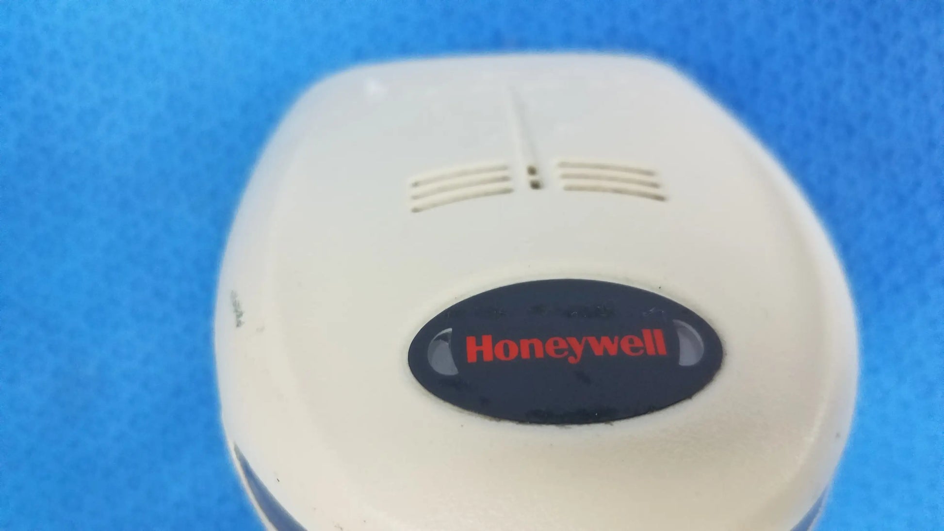 Cream-colored plastic honeywell smoke detector with black oval logo and red lettering in lot of 4 laser barcode scanner for reuse medical equipment