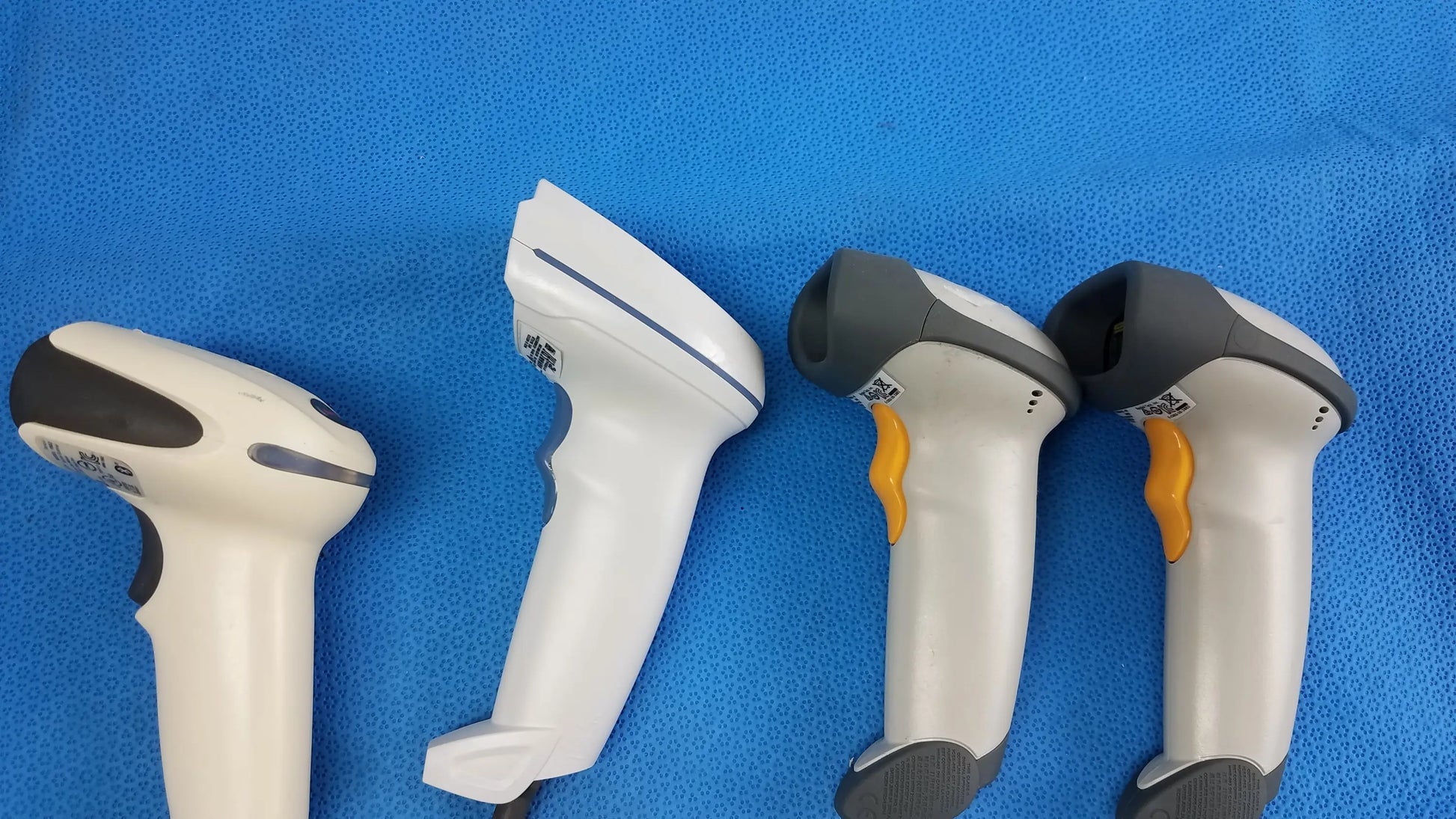 Lot of 4 laser barcode scanner readers with white and gray bodies and orange or black triggers for medical equipment use