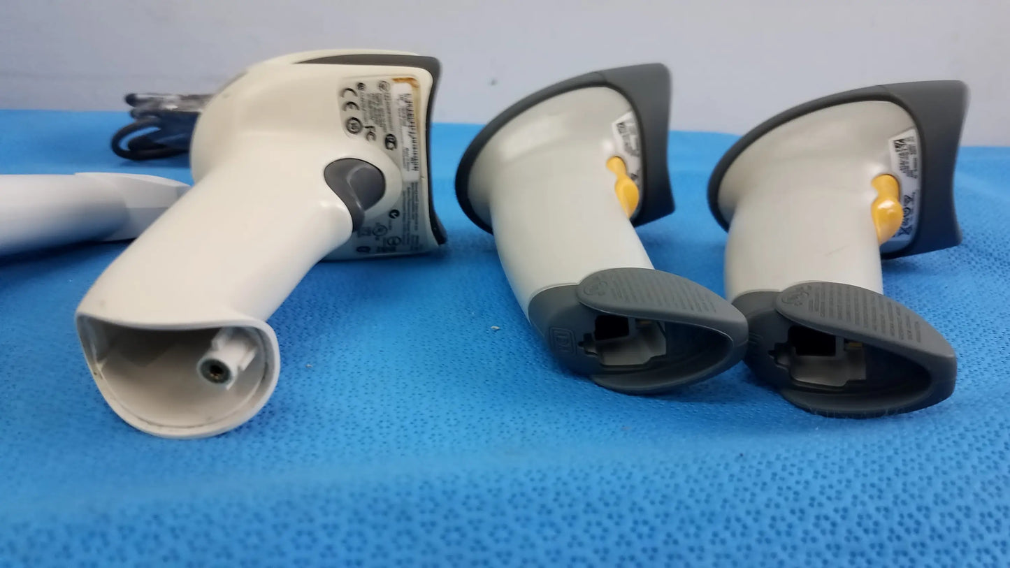 Lot of 4 laser barcode scanner readers featuring three white and gray handheld scanners with black grips and a yellow trigger button for reuse medical equipment