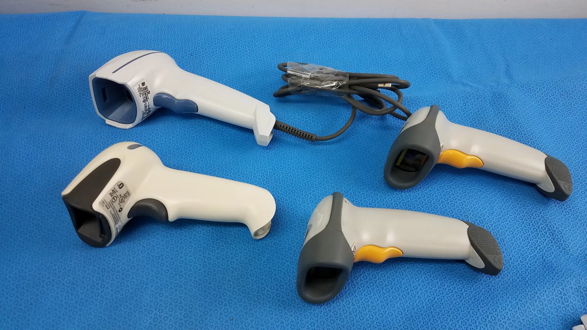 Lot of 4 laser barcode scanner readers with ergonomic grips in white gray and yellow for reuse medical equipment