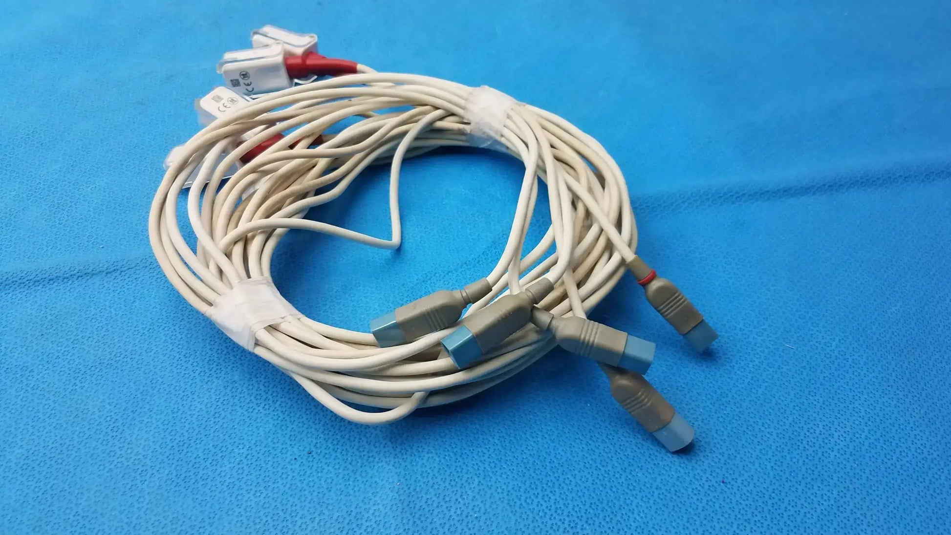 Coiled beige masimo lncs patient cables designed with gray and blue connectors and red and white diagnostic plugs compatible monitoring systems