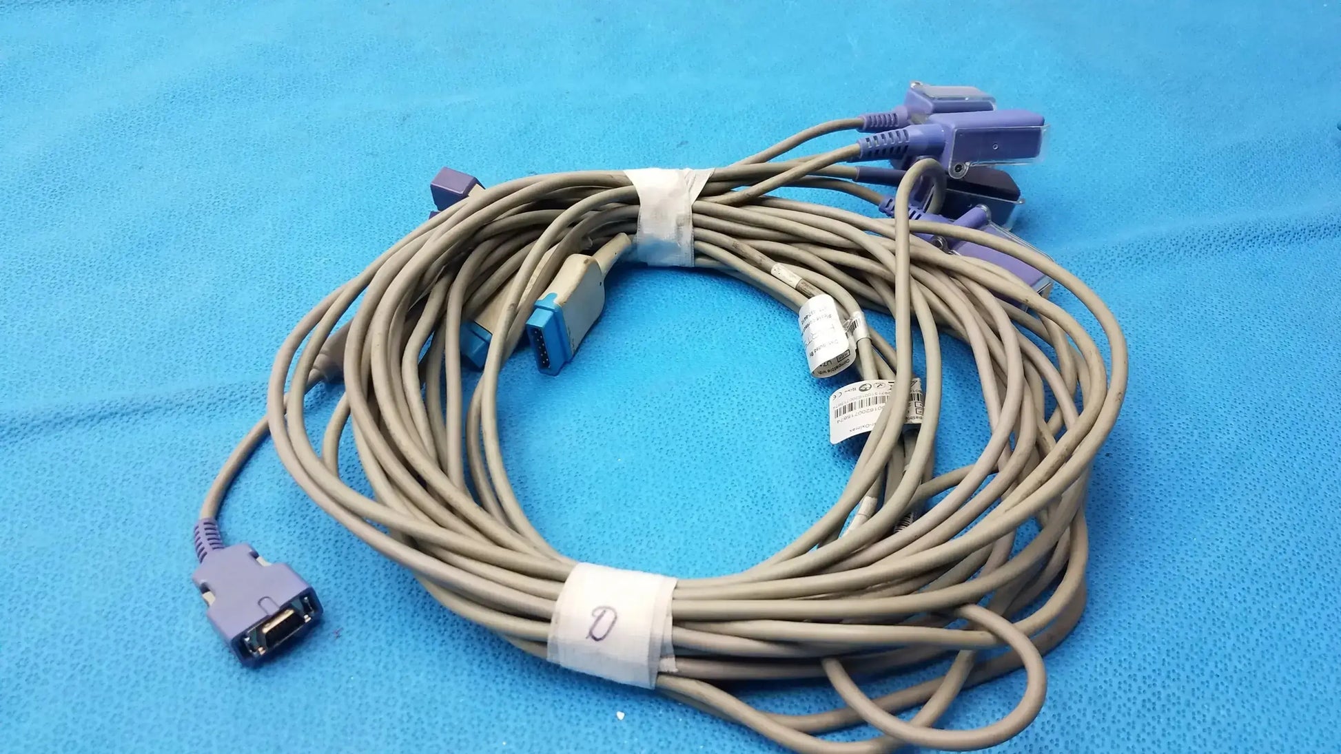Lot of 5 coiled beige Nellcor spo2 adapter extension cables with purple and blue connectors secured by white ties