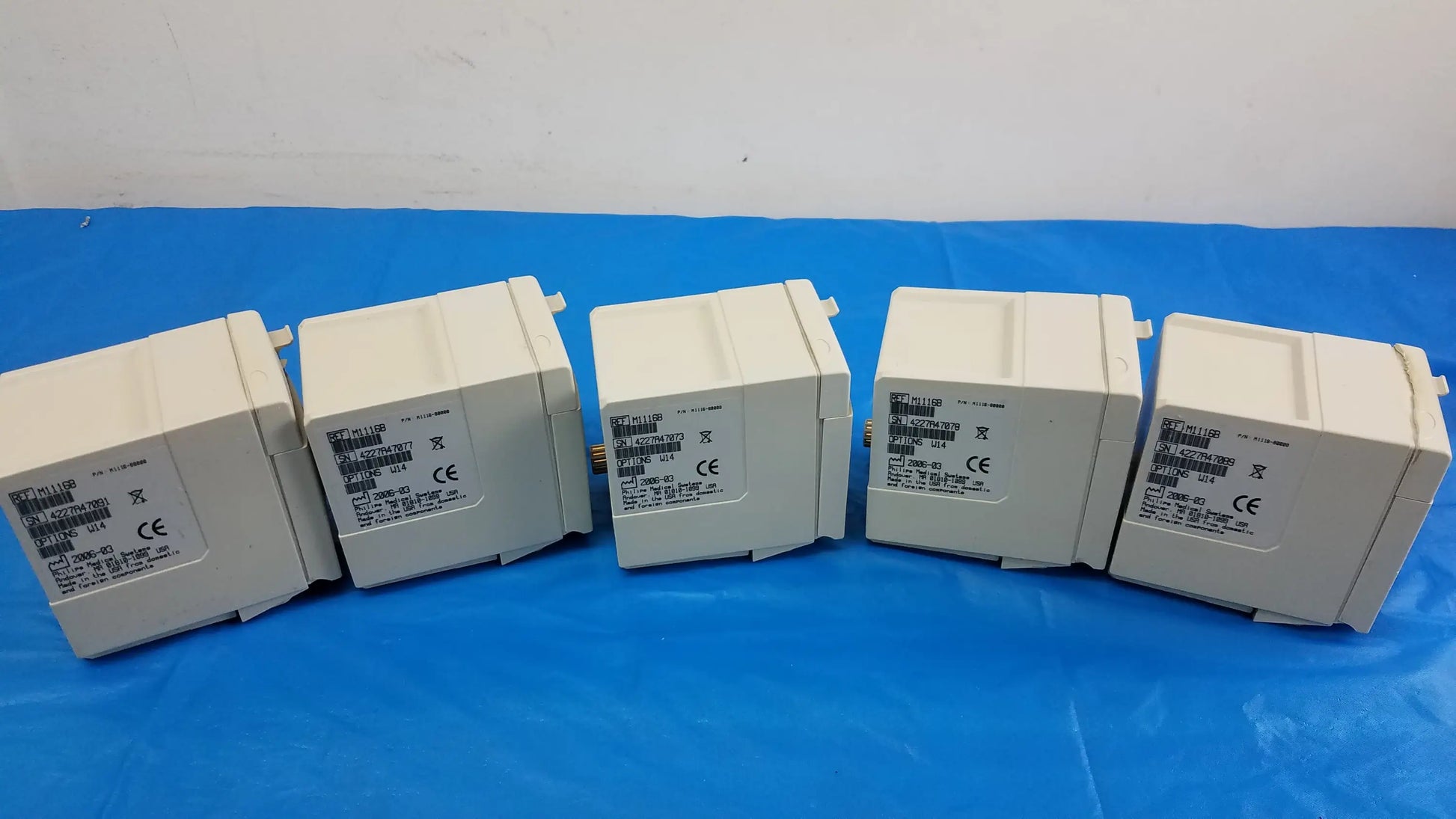 Five off-white plastic philips m1116b recorder modules arranged in a row for medical equipment patient monitoring
