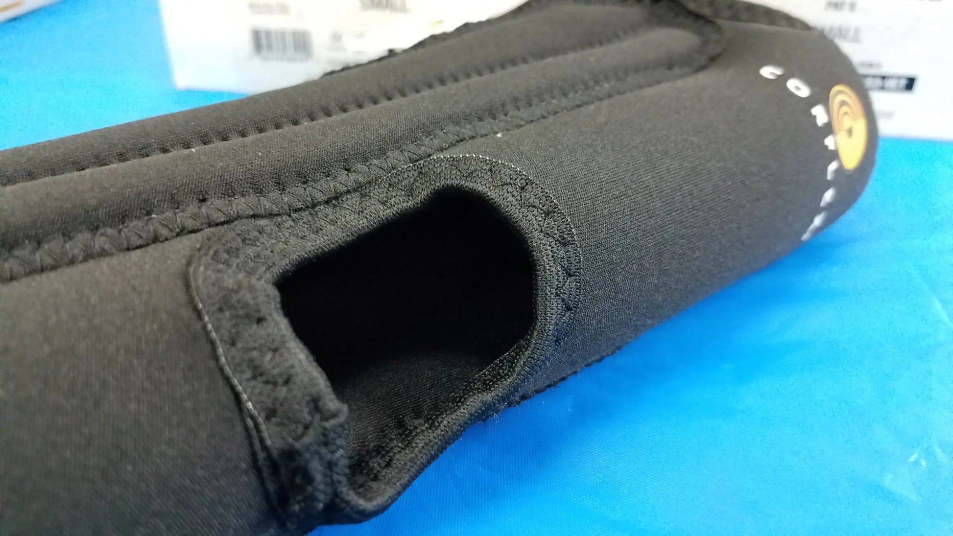 Black neoprene wrist support with reinforced stitching and gold logo shown alongside corflex cooltex knee sleeves medical equipment
