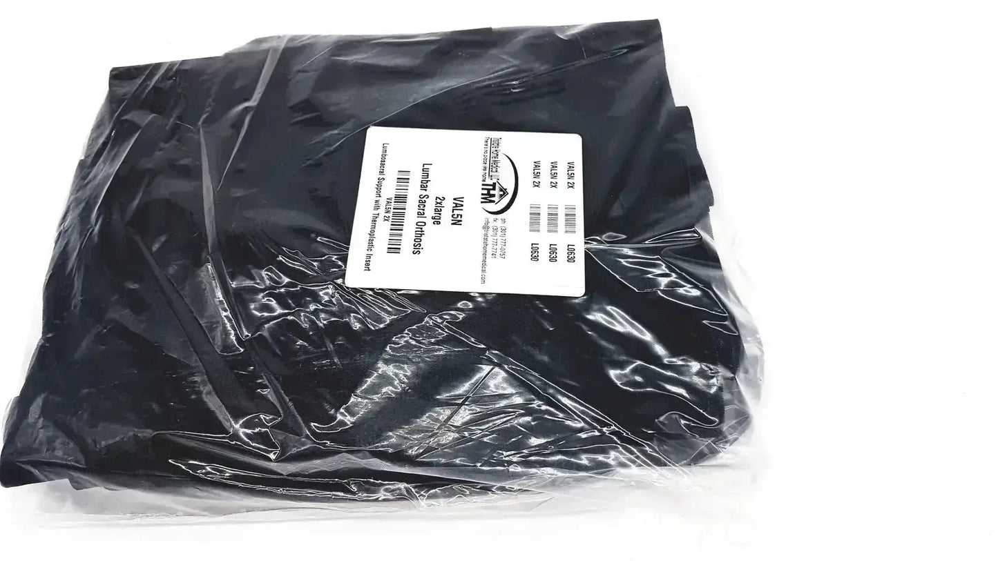 Black plastic bag filled with round chocolate candies beside lumbar sacral orthosis with thermoplastic insert