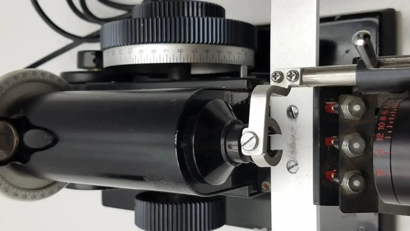 Black cylindrical microscope stage with silver metallic parts and engraved markings on marco model 101 manual lensmeter hospital surplus