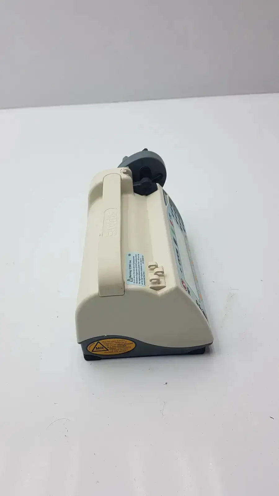Beige plastic handheld vacuum cleaner with black handle and base featuring a pole clamp for hospital surplus biomedical evaluation