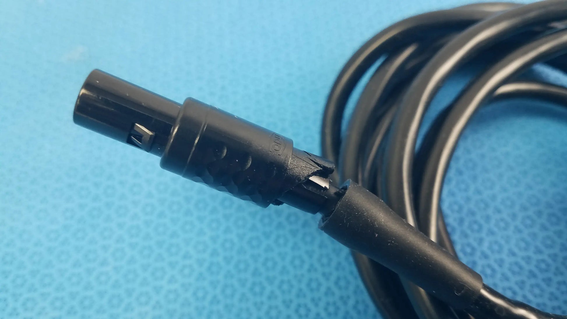Black coiled medical surgical handpiece console extension cable with matte plastic connector for medical equipment use