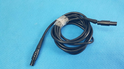 Black coiled medical surgical handpiece console extension cable with two connectors and white label for medical equipment