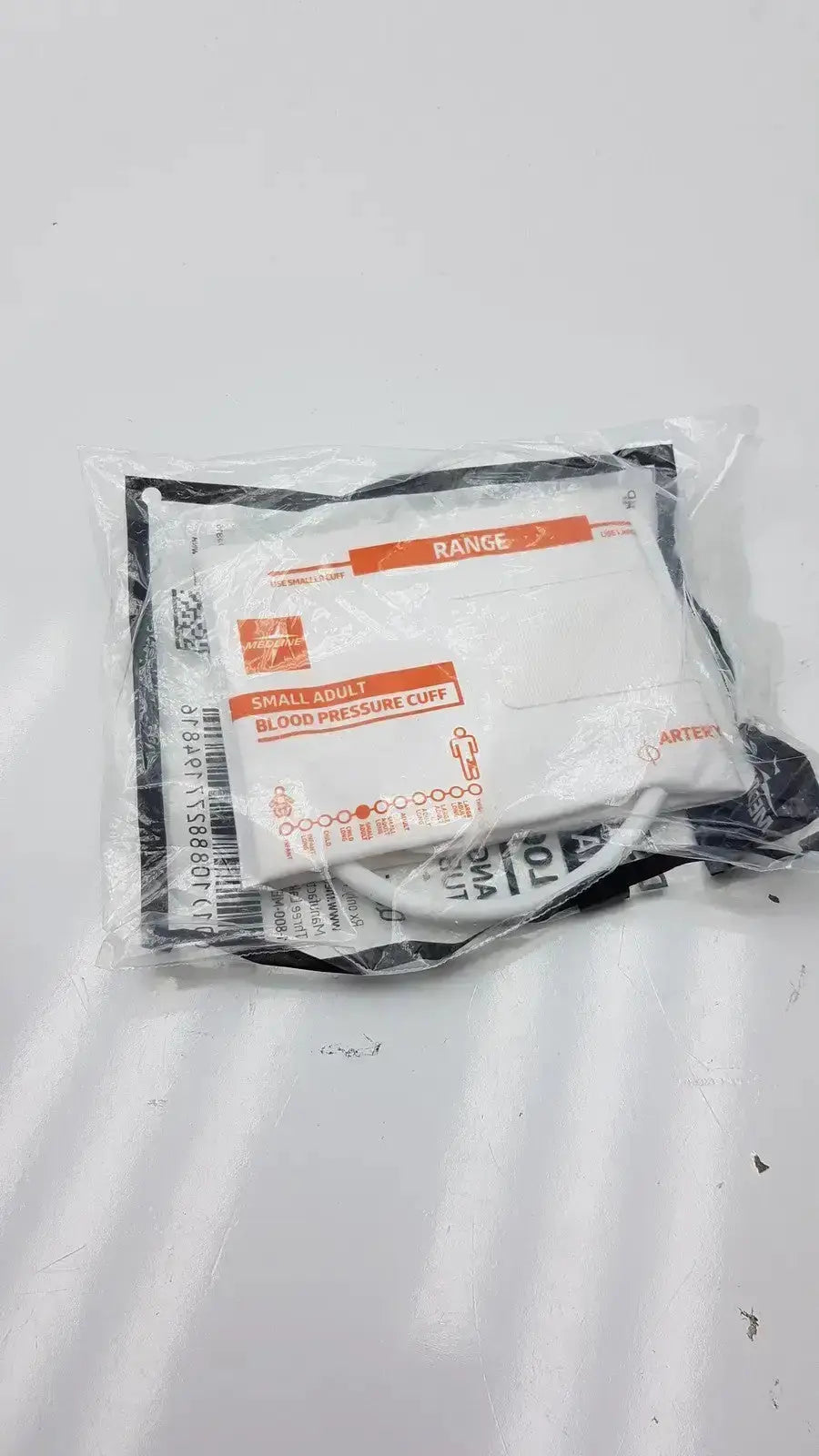 White and black blood pressure cuff in clear plastic packaging with orange labeling medline disposable cuff range 20.5 - 28.5 cm