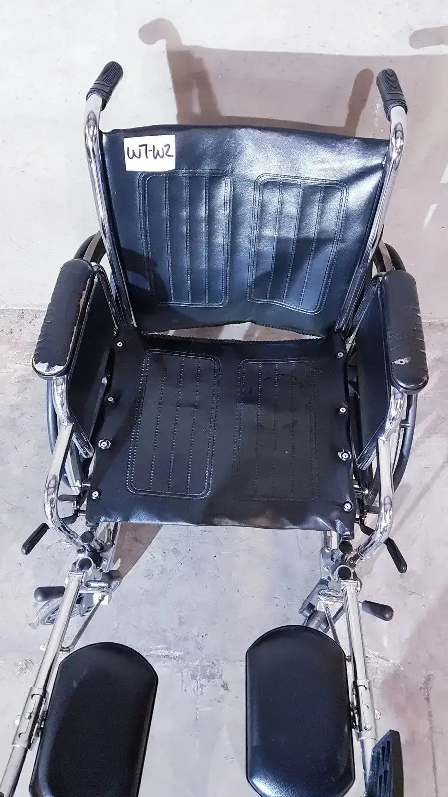 Black leather-backed medline k1206n22e manual wheelchair for adult with chrome frame and adjustable footrests viewed from back