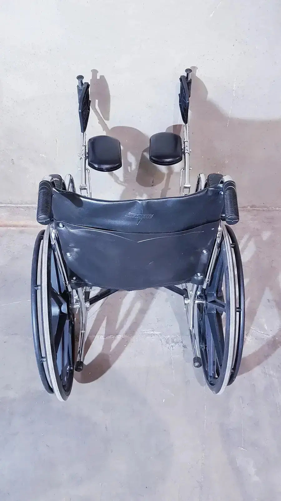Black leather-backed medline k1206n22e manual wheelchair with silver metal frame and black padded seat cushions