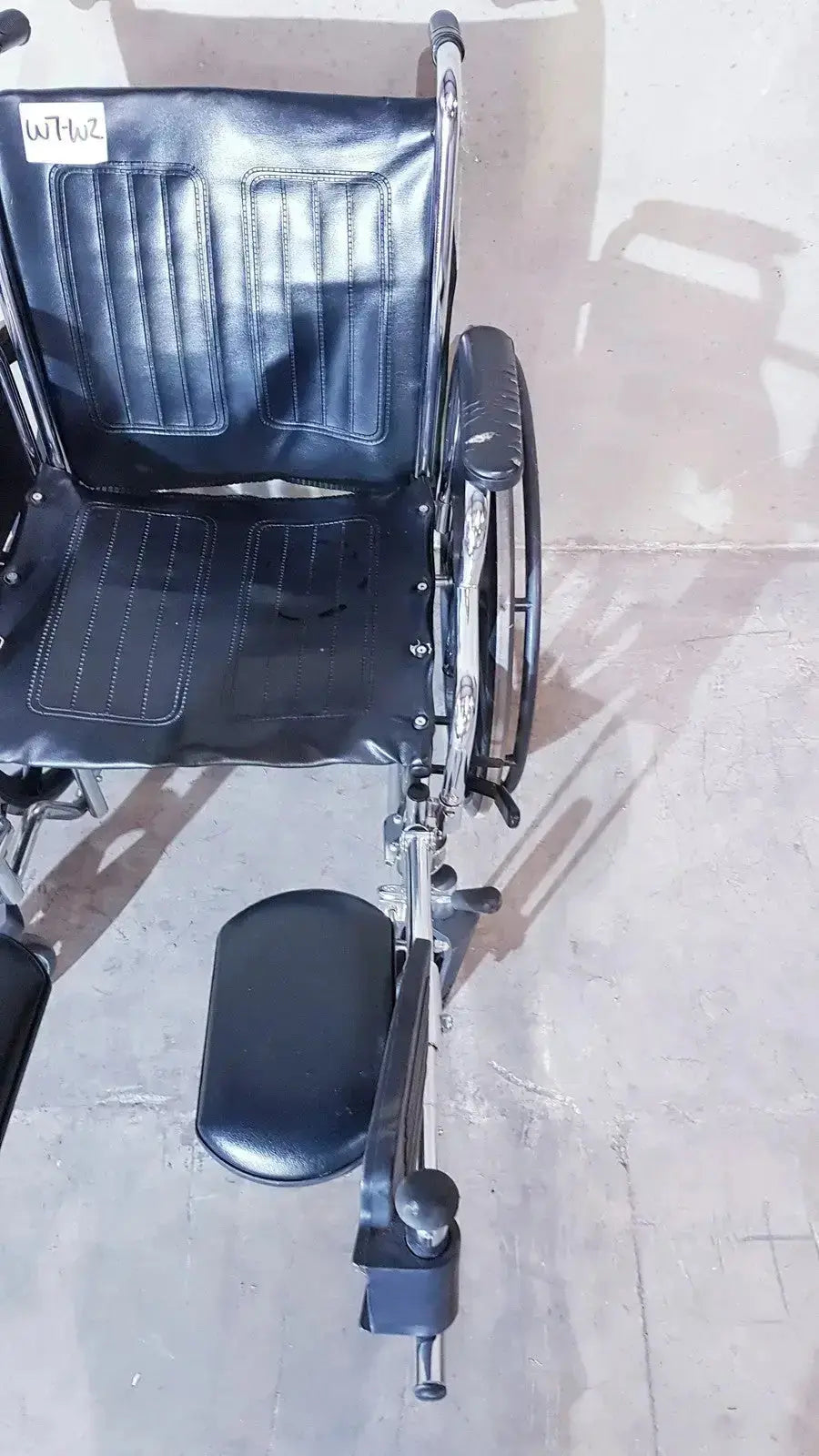 Black leather-backed medline k1206n22e manual wheelchair for adult with chrome metal frame and footrest viewed from back
