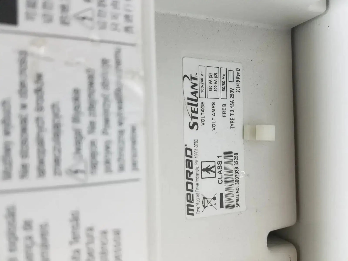 White plastic label with black text and barcode on medrad stellant ct power supply for power supply identification