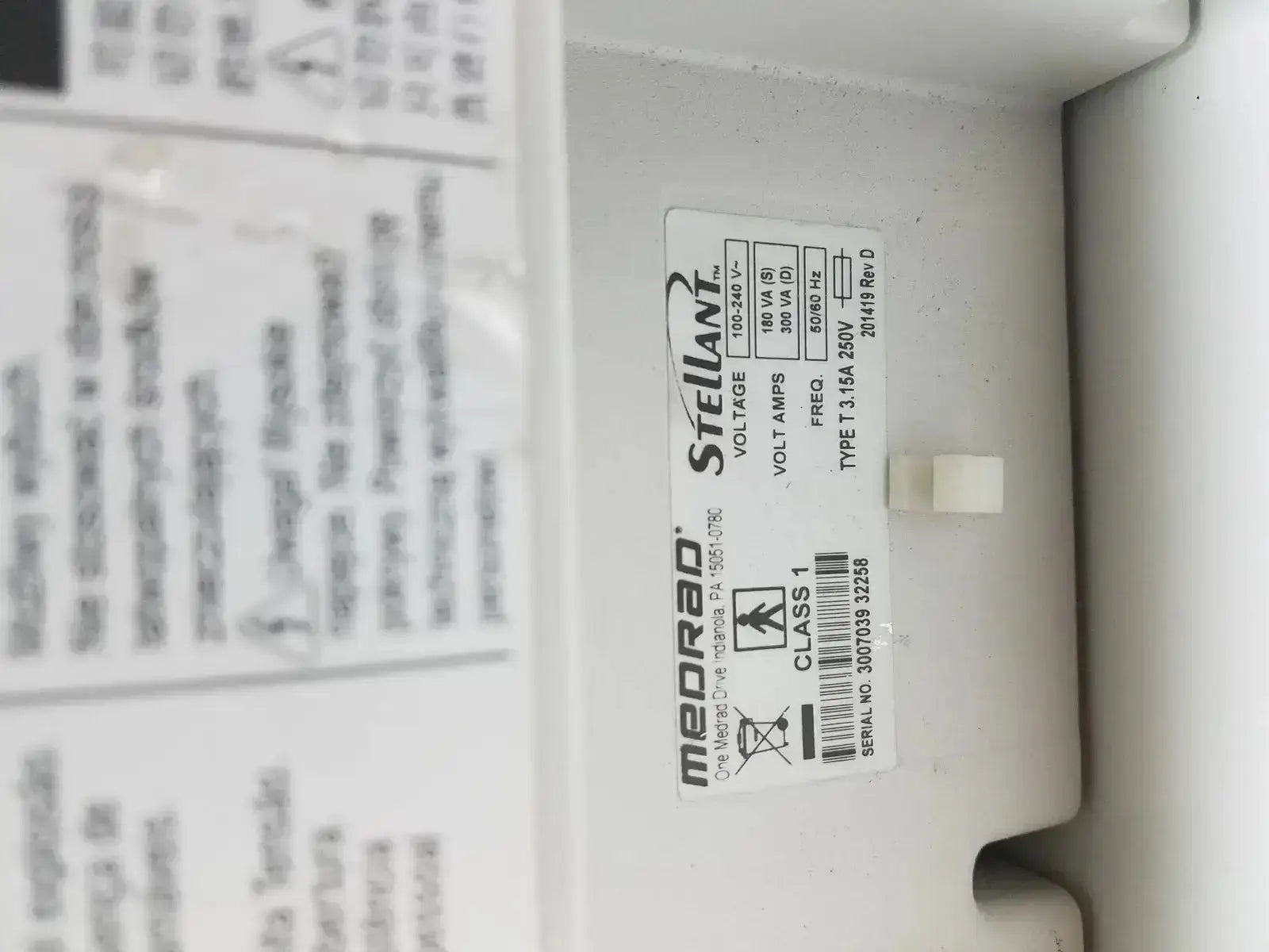 White plastic label with black text and barcode on medrad stellant ct power supply for power supply identification