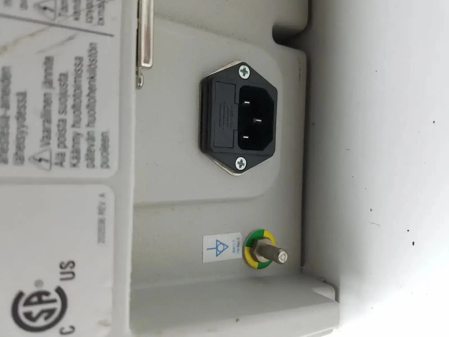 Black hexagonal power plug with two flat prongs on light gray plastic housing of medrad stellant ct power supply