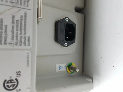 Black hexagonal power plug with two flat prongs on light gray plastic housing of medrad stellant ct power supply