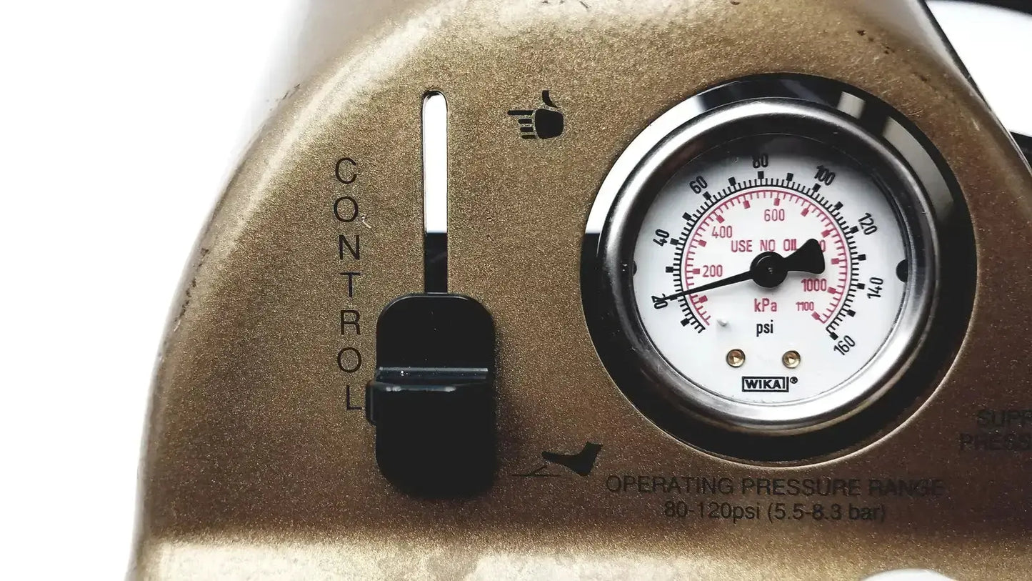 Gold-colored wika pressure gauge with black dial and silver bezel mounted on midas rex legend gold pneumatic panel