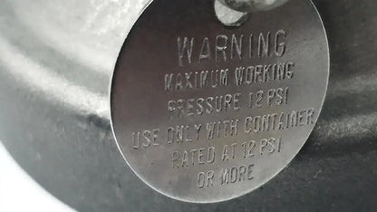 A dark metallic circular warning label with safety instructions on the back of a micro matic inlet keg coupler