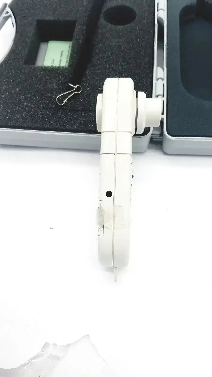 White plastic handheld Micro Medical MicroCO carbon monoxide monitor with segmented body and circular attachment point