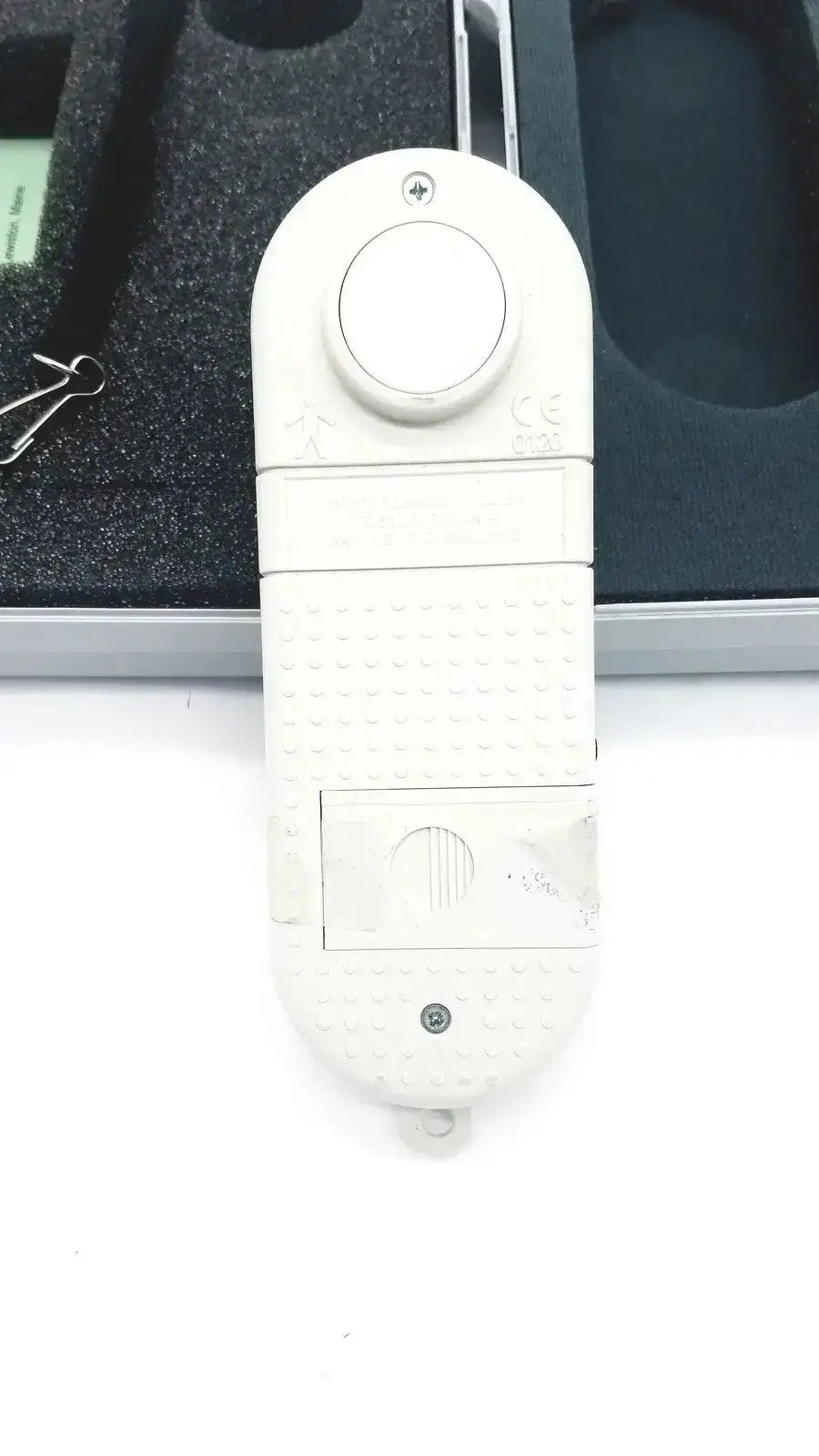 White plastic remote control with textured grip and circular button on top for micro medical microco carbon monoxide monitor case