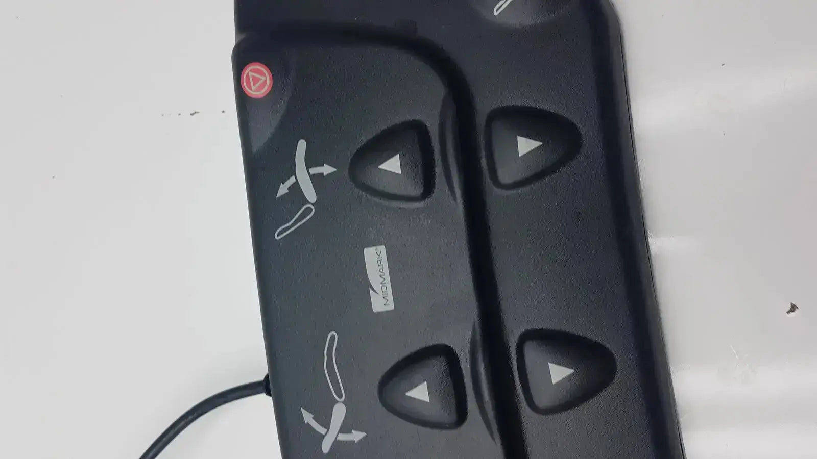 Black plastic midmark 647 podiatry chair foot control panel with four triangular buttons and red circular button