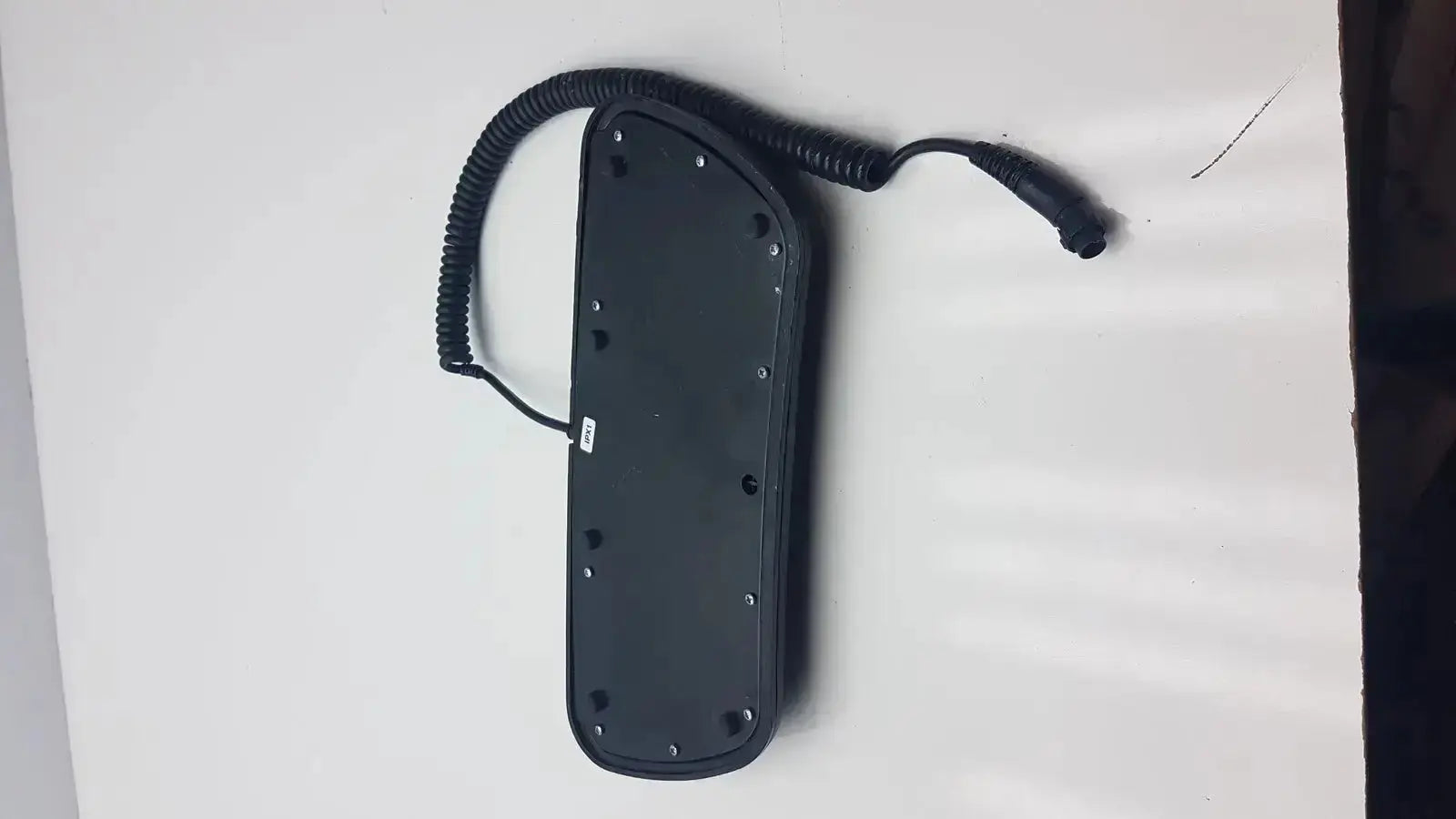 Black rectangular Midmark 647 podiatry chair foot control with coiled cable and multiple screw holes on back side