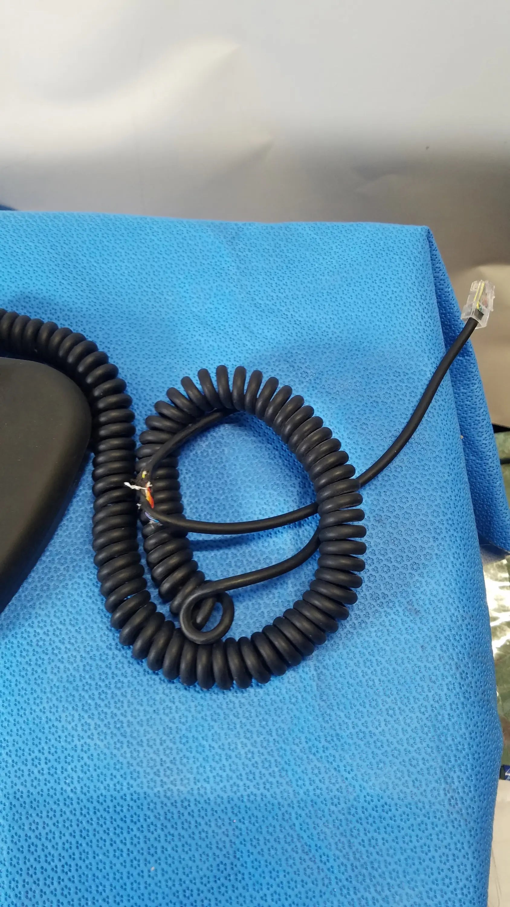 Black coiled telephone cord with clear rj45 connector on midmark qe ipx1 wired foot controller for medical equipment use