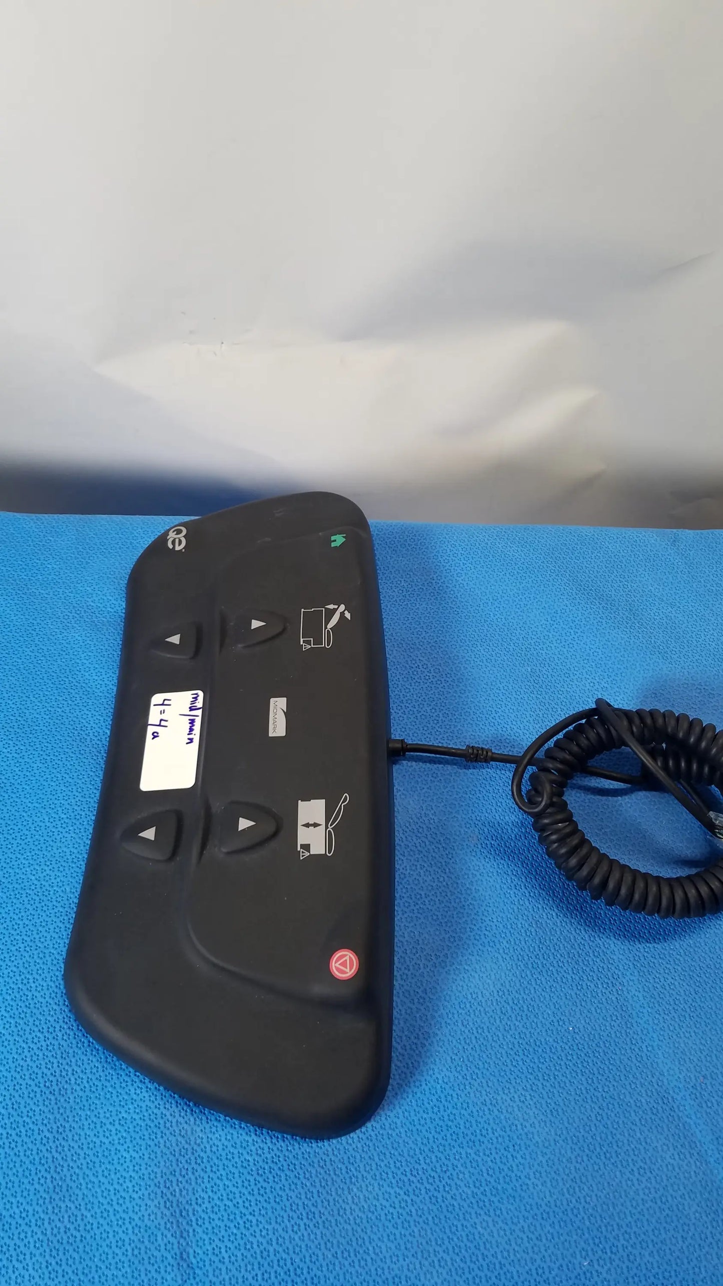 Black ergonomic midmark qe ipx1 wired foot controller with directional buttons and coiled cable for medical equipment use