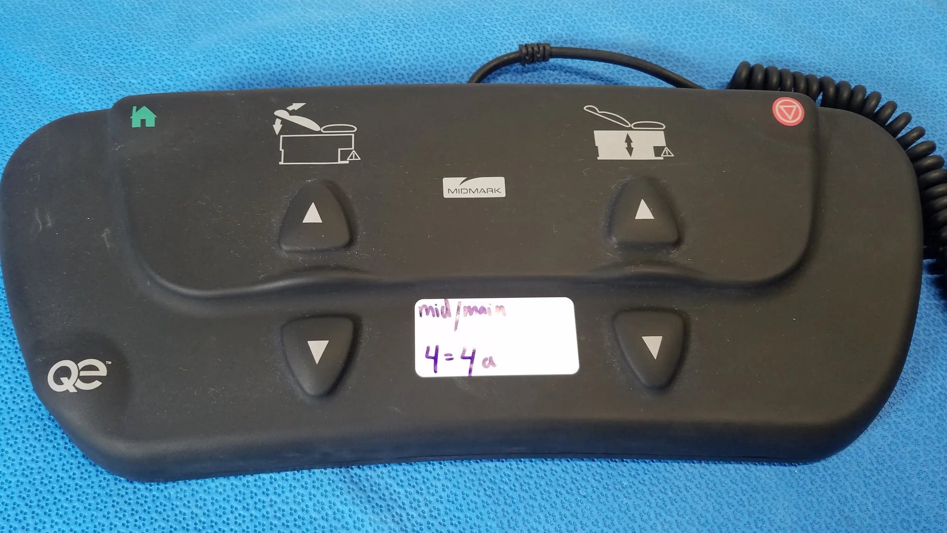 Black plastic midmark qe ipx1 wired medical equipment control panel with four triangular buttons for pot functions