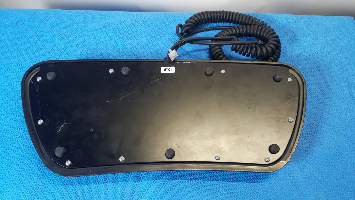 Black plastic keyboard base of midmark qe ipx1 wired foot controller with coiled black cable and silver screws for medical equipment reuse
